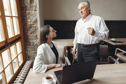 Image of an old man talking to a young employee.