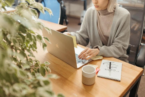 Woman sitting in front of a silver laptop.